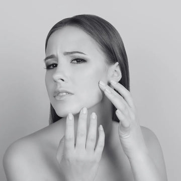 Woman examining her face for dry skin and blemishes, focused on skincare concerns and solutions.